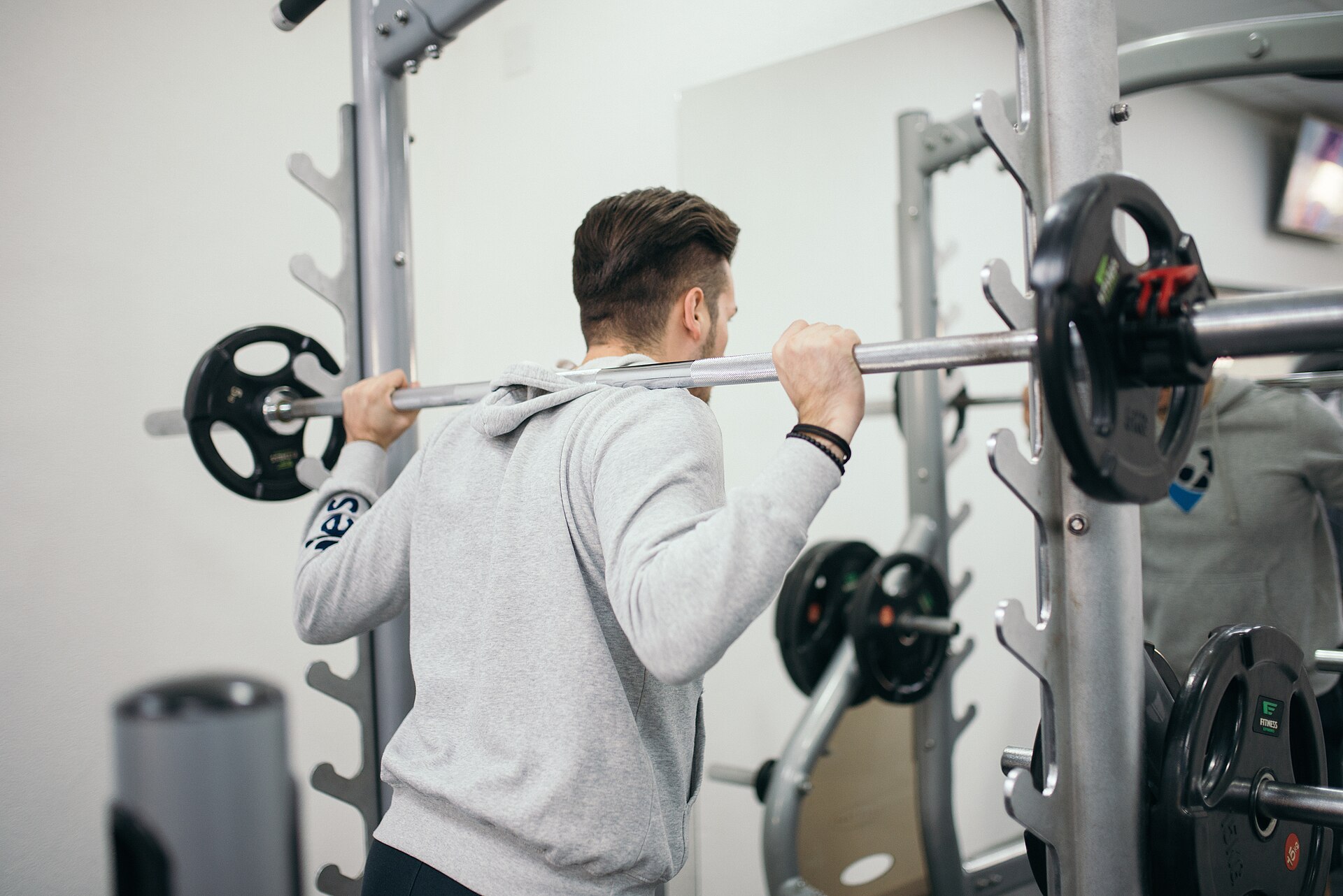 Eine Person trainiert in einem Fitnessstudio mit einer Langhantel.